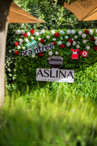 a bush with roses on it a banner saying "aslina by mtsiki biyela" and a banner of Braintree's logo outside the Accelerate Action: A Creative Brunch for Women in Business Leadership function - 2