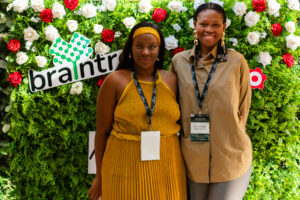 two woman standing in front of a rose bush smiling at the camera at the Accelerate Action: A Creative Brunch for Women in Business Leadership function