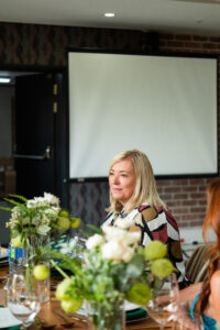 woman in a multicoloured outfit sitting at a dining table at the Accelerate Action: A Creative Brunch for Women in Business Leadership function
