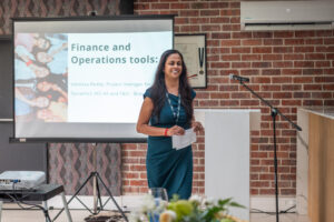 woman in a greenish blue dress walking from a podium after speaking on "Finance and Operations tools" at the Accelerate Action: A Creative Brunch for Women in Business Leadership function