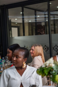 women sitting at dining tables smiling at an off-camera speaker at the Accelerate Action: A Creative Brunch for Women in Business Leadership function