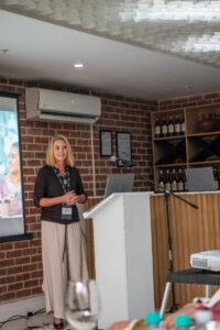 woman in beige pants and a dark brown shirt speaking at the Accelerate Action: A Creative Brunch for Women in Business Leadership function