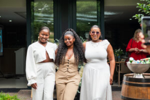 three women [osing in front of the "Bloom Bar" sign at the Accelerate Action: A Creative Brunch for Women in Business Leadership function