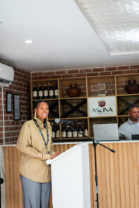 woman in light brown top and grey trousers speaking at the Accelerate Action: A Creative Brunch for Women in Business Leadership function