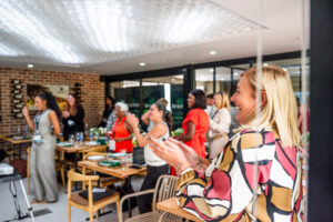 women laughing and cheering at the Accelerate Action: A Creative Brunch for Women in Business Leadership function