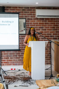 woman in a yellow dress speaking at the Accelerate Action: A Creative Brunch for Women in Business Leadership function
