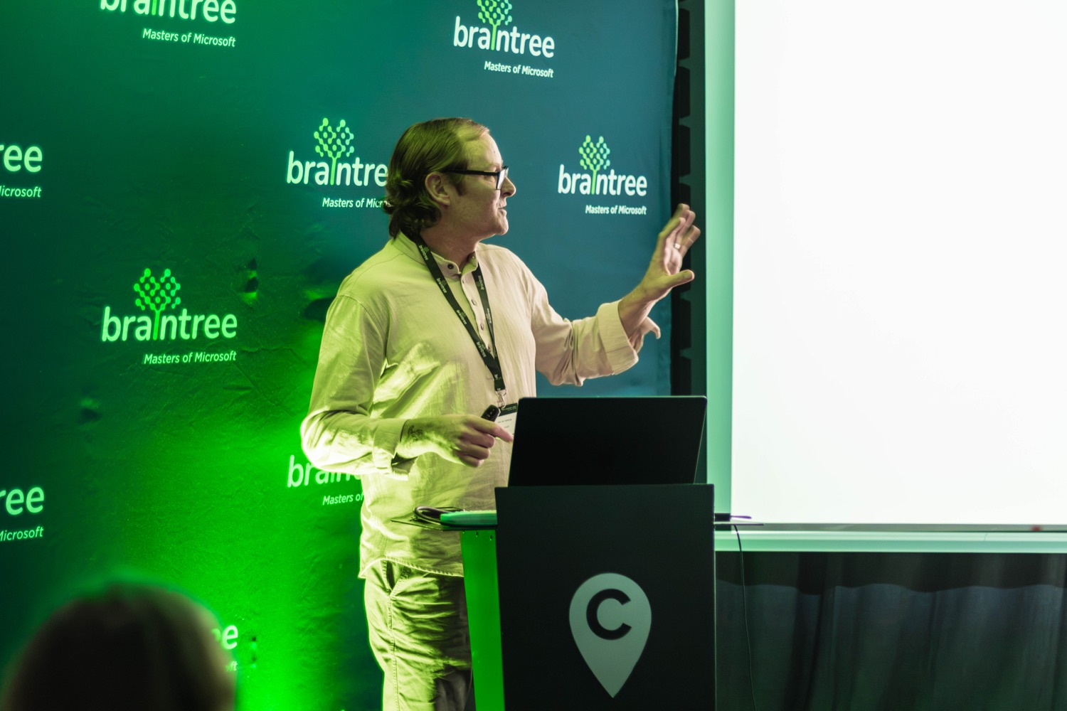 A speaker making a point beside the branded stage