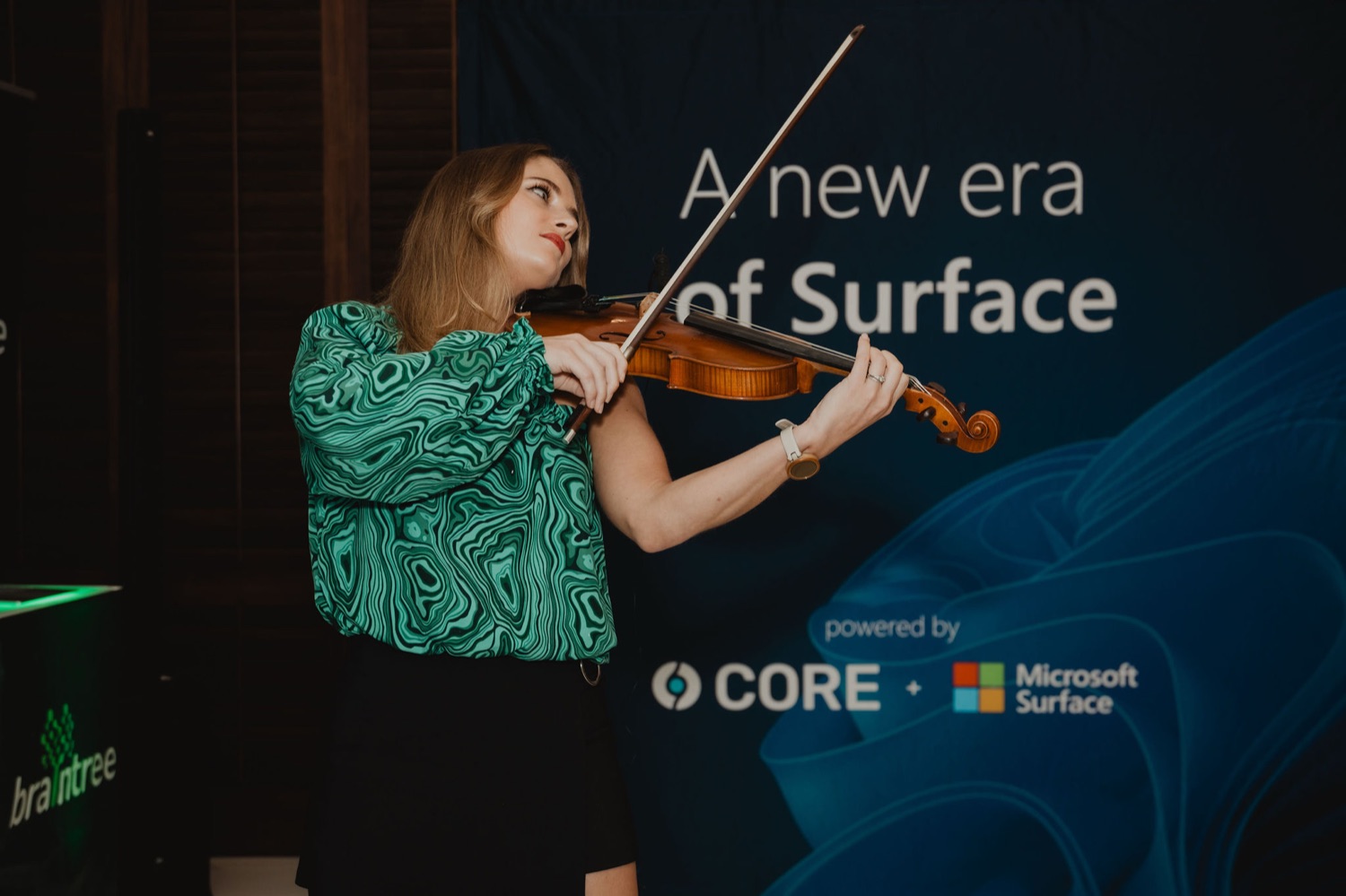 A violinist performing beneath the new era of Surface banner
