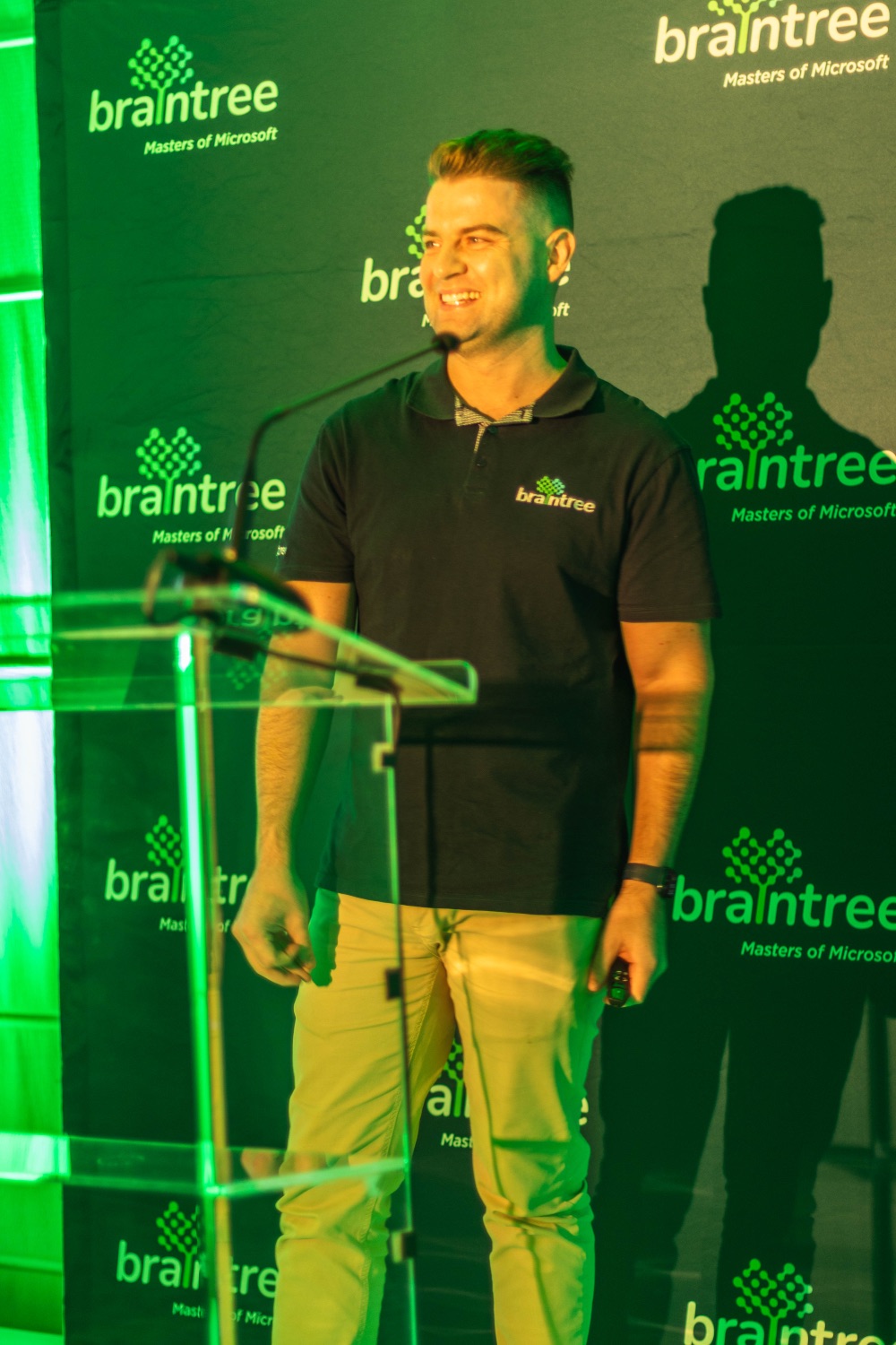 A speaker smiling at the lectern in front of the Braintree backdrop
