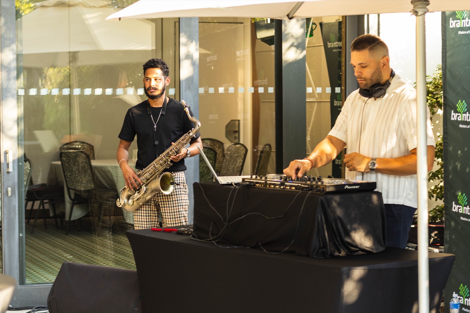 A live saxophonist and DJ entertaining guests in front of a Braintree branded backdrop