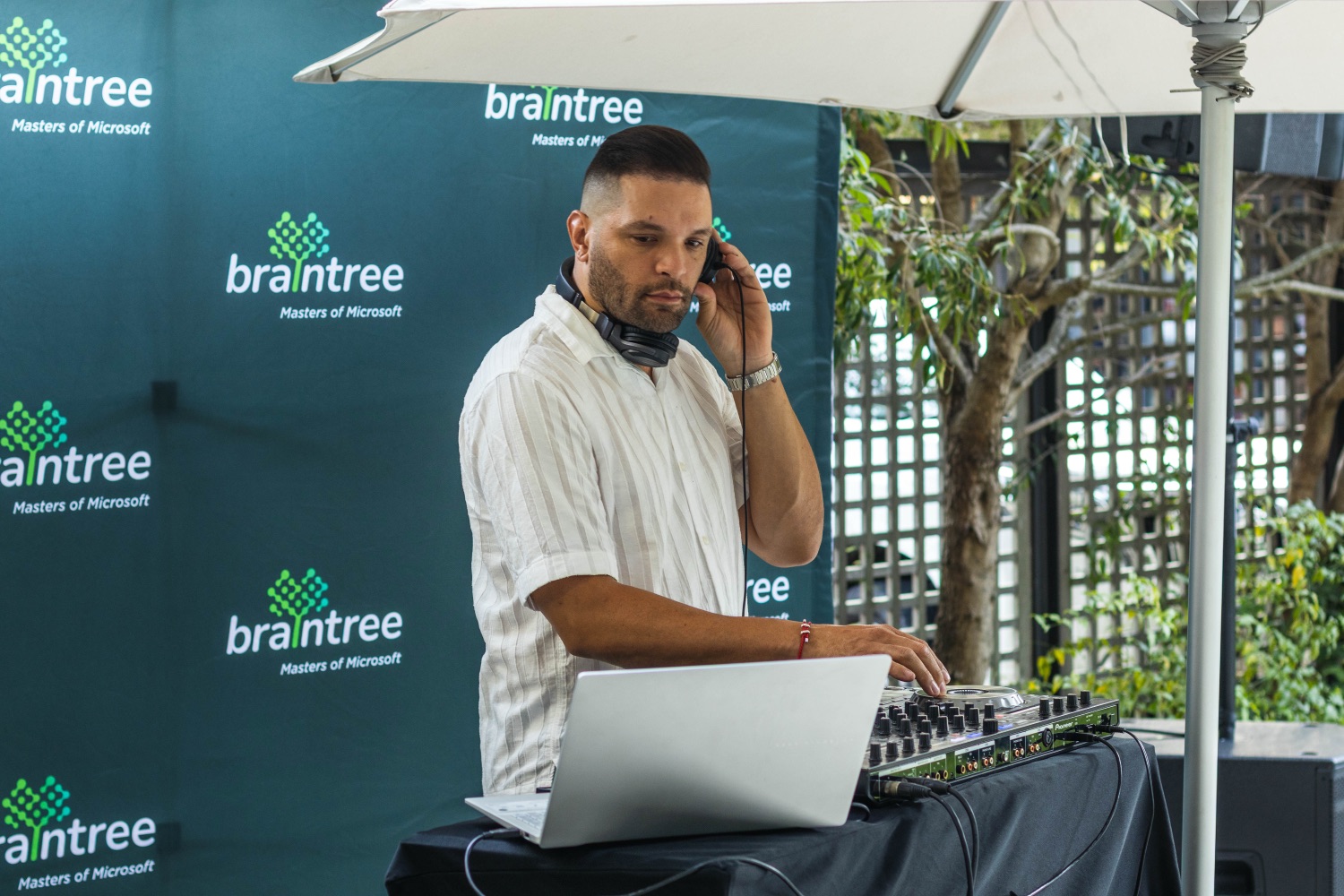 A DJ mixing on a laptop and controller against a Braintree branded backdrop