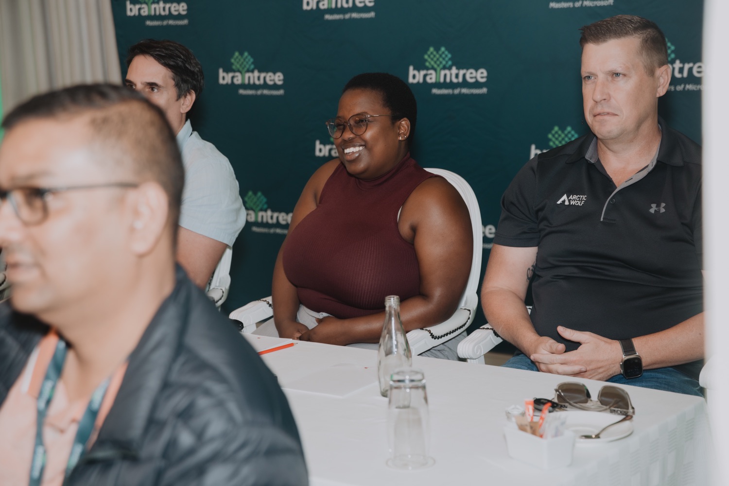 Guests smiling during a panel discussion in front of the Braintree backdrop