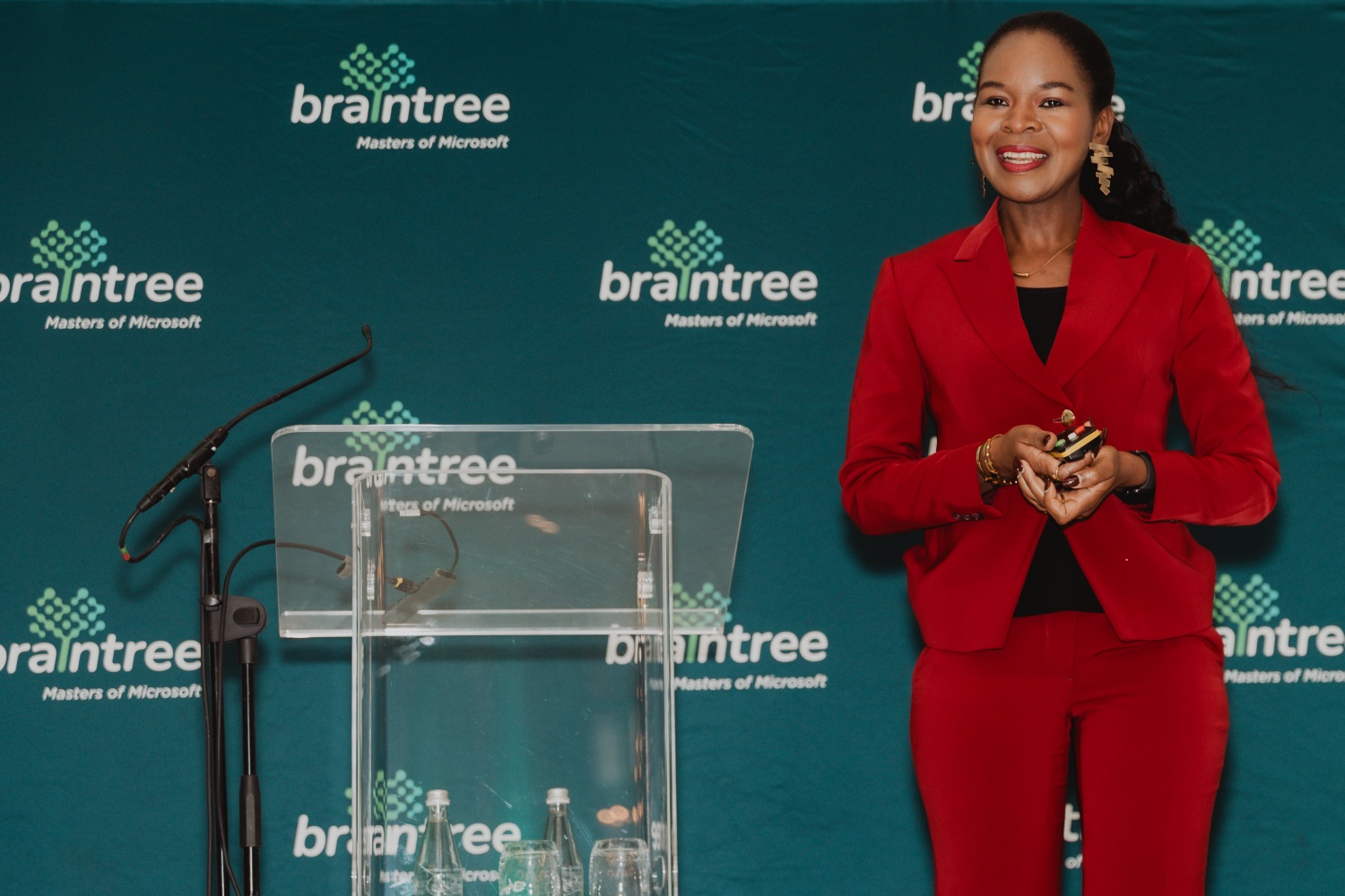 A keynote speaker in a red suit addressing the room from the Braintree podium
