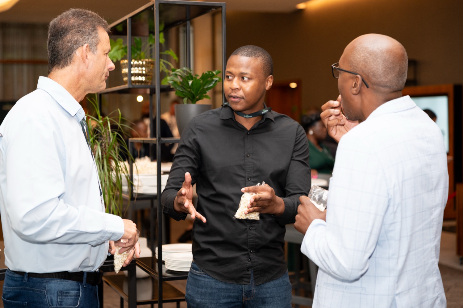 Three guests in animated conversation during a networking break.