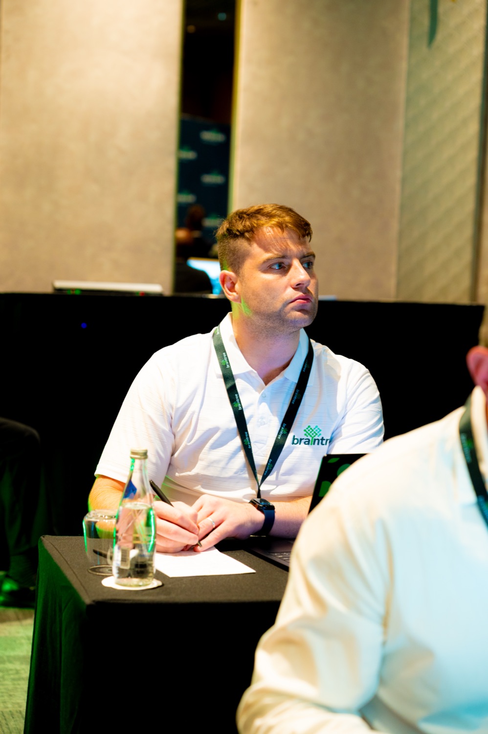 An attendee wearing a Braintree lanyard listening during a session
