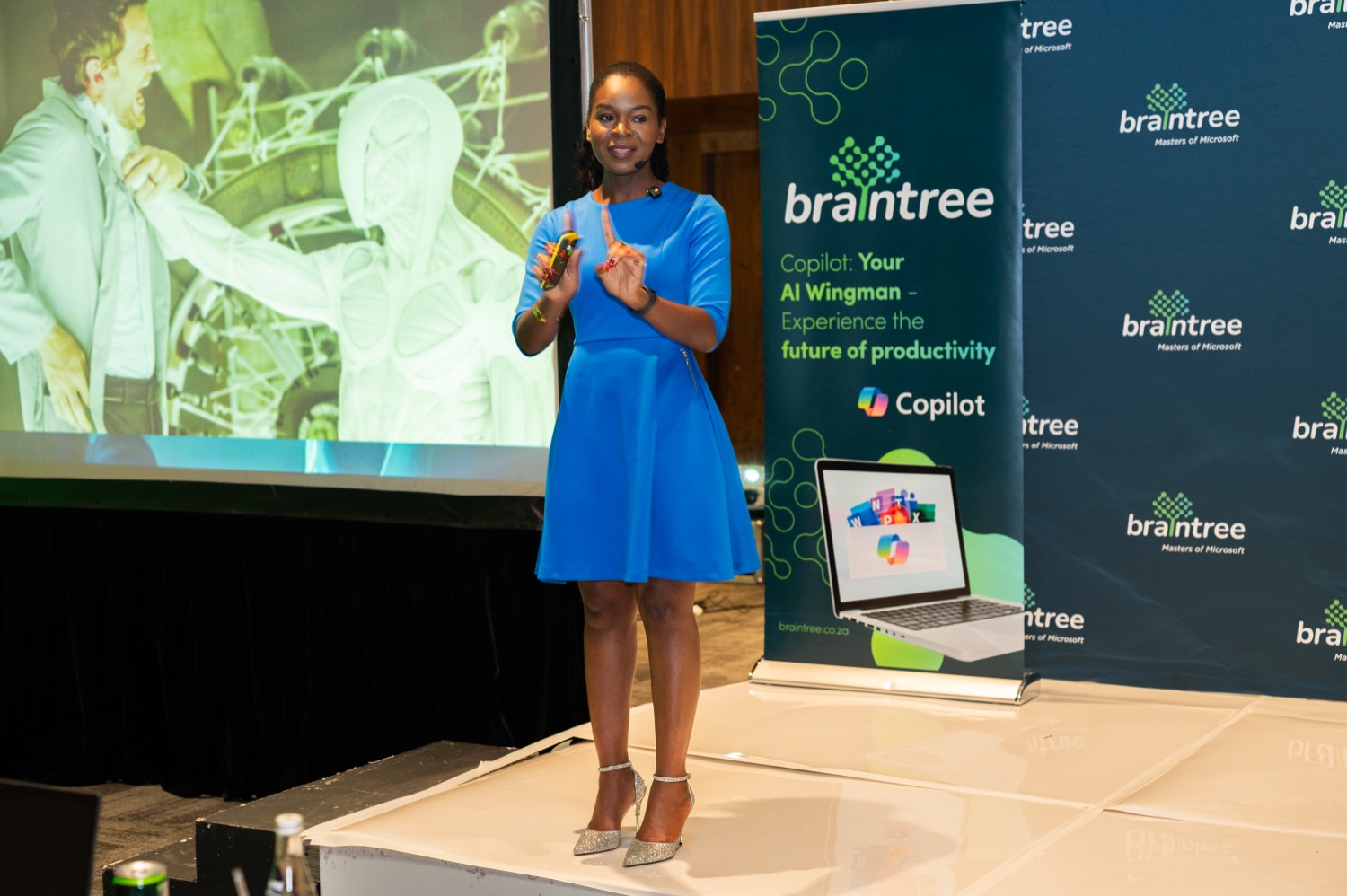 A speaker gesturing while presenting beside Braintree branding