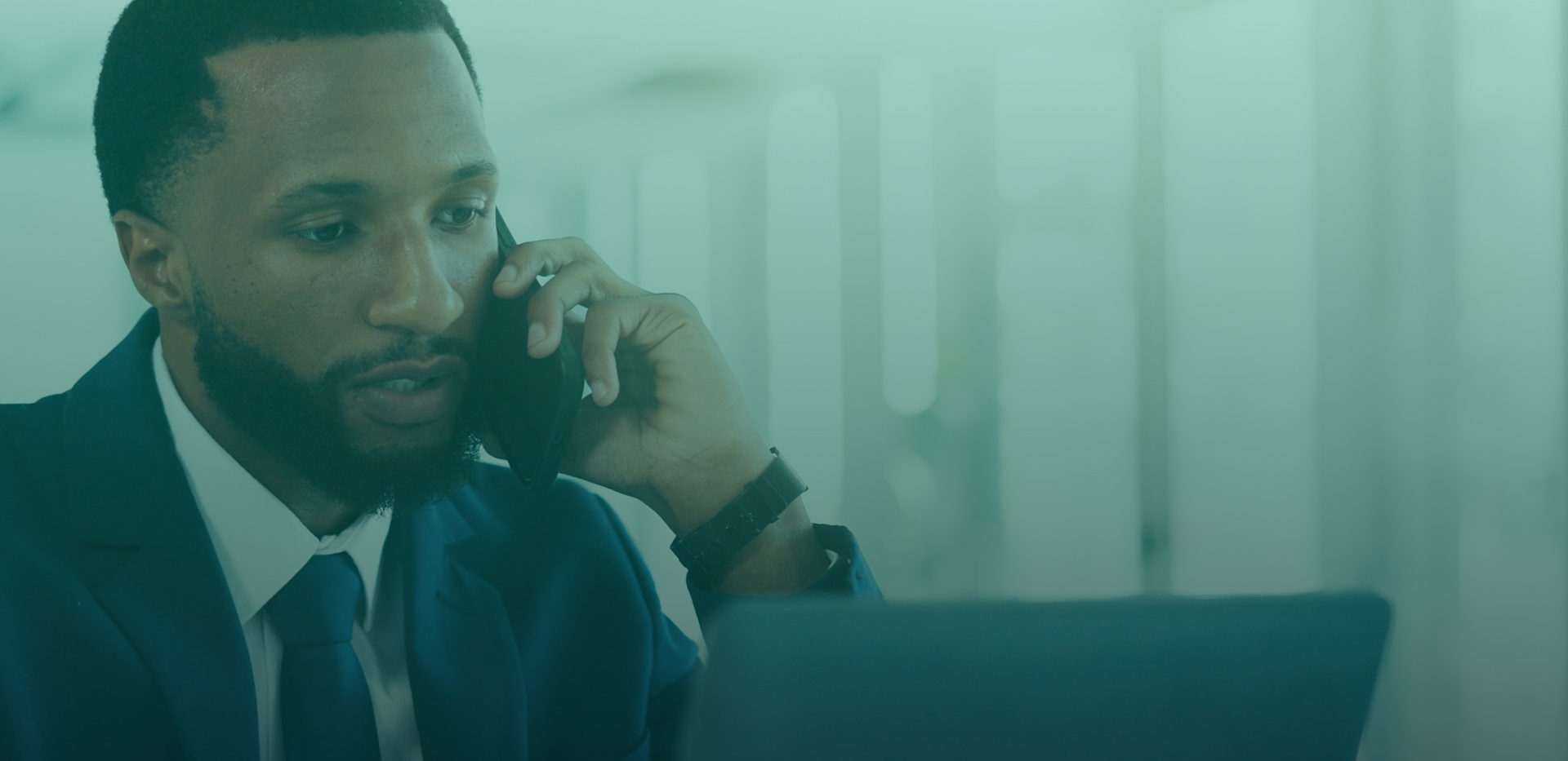 Business professional speaking on a phone beside a laptop