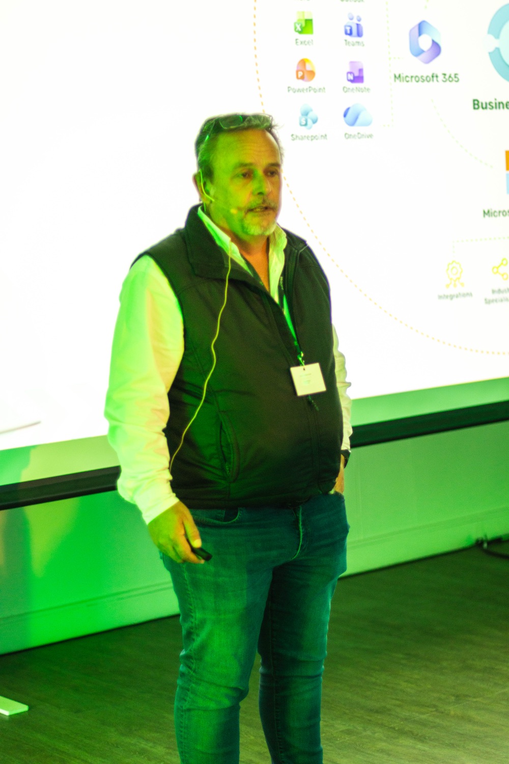 A speaker presents to the room in a well-lit shot