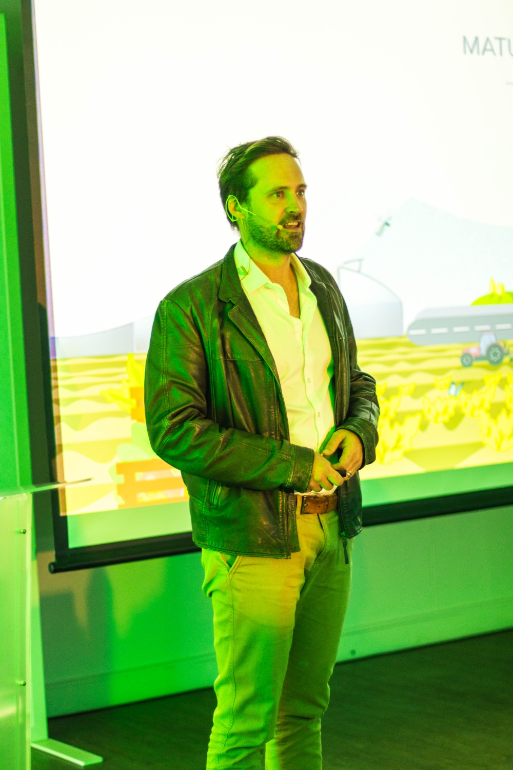 A presenter stands beside the projected Matumi solution visual