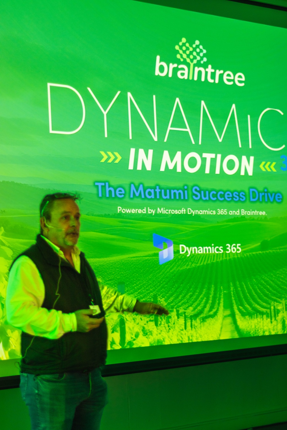 The Dynamics in Motion event branding on screen with a speaker alongside
