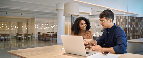 Two colleagues reviewing a CRM stack at a laptop