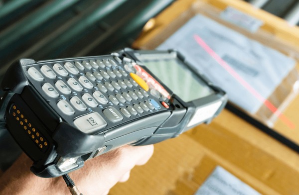 A handheld barcode scanner reading a package label